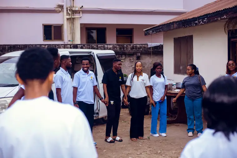Bill Foundation TZ volunteers standing in a circle holding hands before an outreach begins