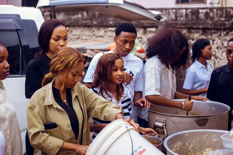 Bill Foundation TZ volunteers serving food from large cooking pots before an evening street outreach in Dar es Salaam