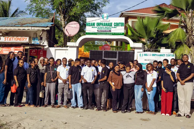 A large group of Bill Foundation TZ volunteers outside the gate of Hisani Orphanage Centre, Kibada, Kigamboni