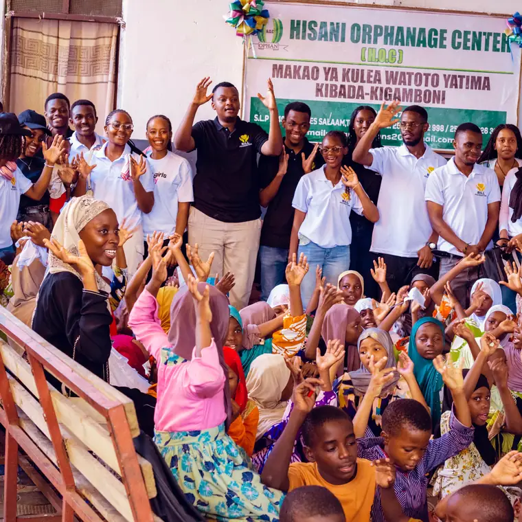 Children and Bill Foundation TZ volunteers with hands raised at Hisani Orphanage Centre, Kibada, Kigamboni